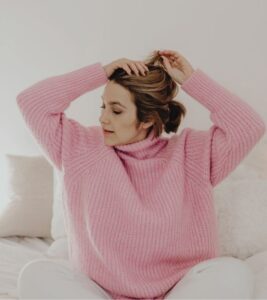 A Woman in Pink Sweater Fixing Hair